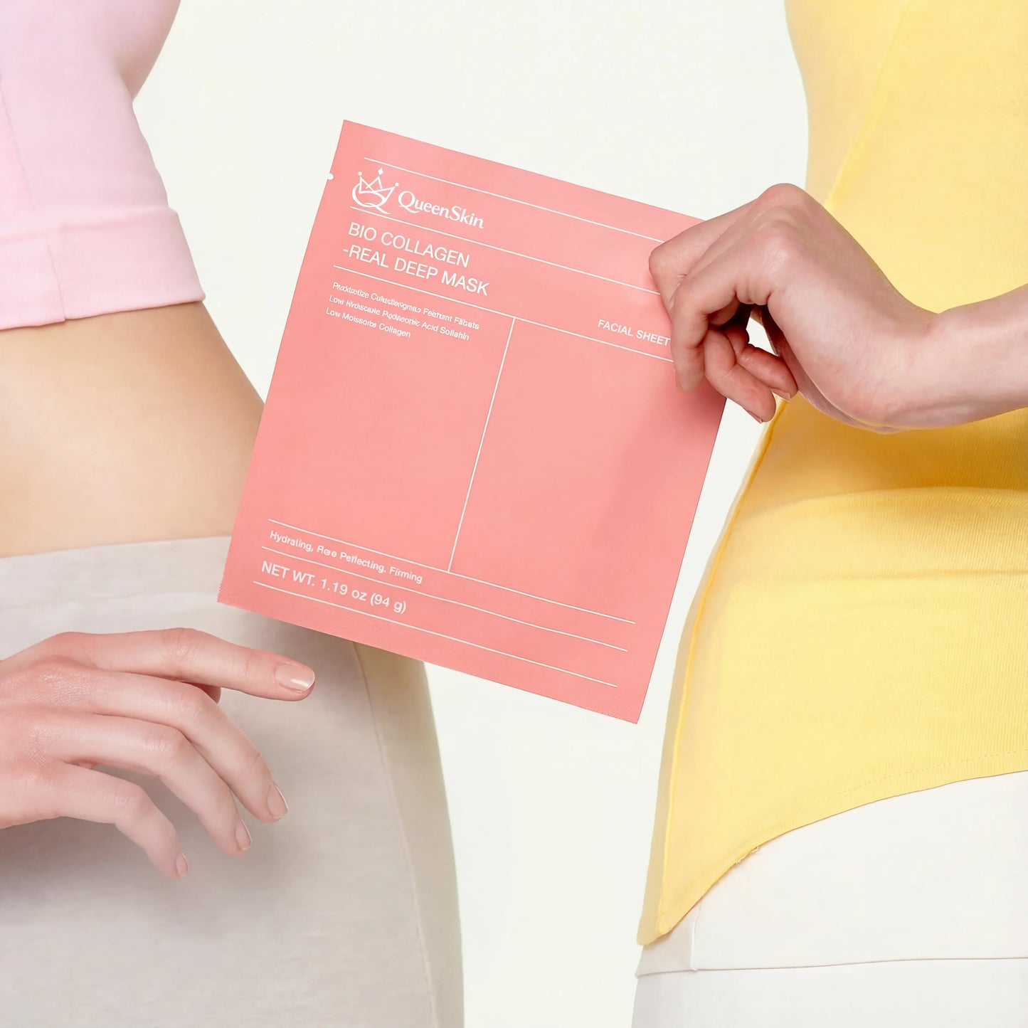 Hands holding QueenSkin Bio Collagen Real Deep Mask pink packaging, skincare product close-up