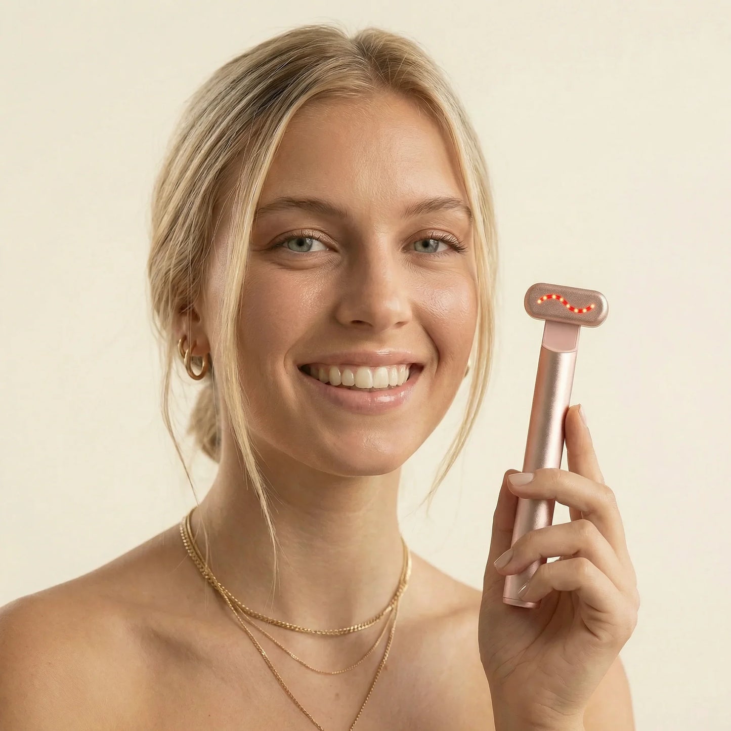 Smiling woman holding QueenSkin microcurrent skincare device with LED lights