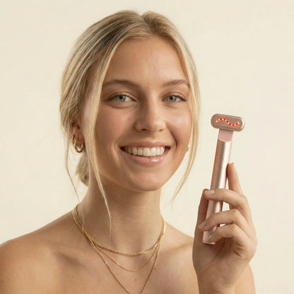 Smiling woman holding QueenSkin microcurrent skincare device with LED lights