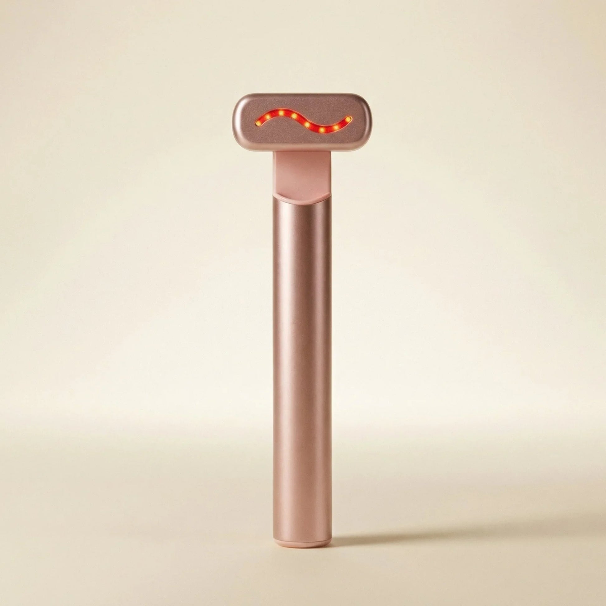 QueenSkin rose gold microcurrent facial device with LED light on beige background