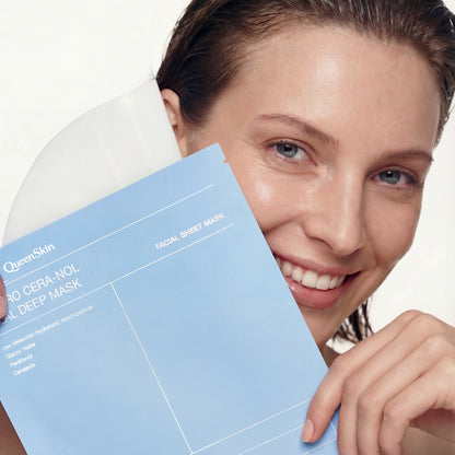 Smiling woman holding QueenSkin facial sheet mask package near her face, clear glowing skin